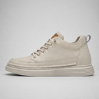 A single low-top lace-up sneaker in a light cream or off-white suede-like material, shown in a side profile against a neutral light gray background.